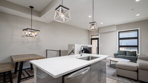 Una cocina moderna con una isla central, un área de comedor con un banco y una sala de estar con un sofá y una mesa de centro.
