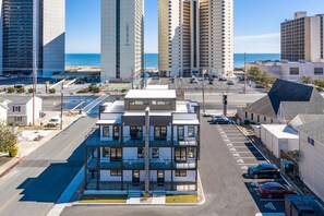 A modern multi-story hotel with a flat roof, large windows, and a parking lot with several cars. - Stunning 2 story luxury villa on 104th Street (Ocean City)