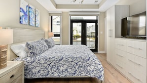 Un dormitorio con cama, ventilador de techo, televisor y vistas al exterior.