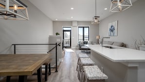 Una cocina moderna con una isla central, taburetes de bar e iluminación colgante.