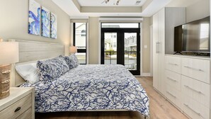 Ein Schlafzimmer mit Bett, Deckenventilator, Fernseher und Blick ins Freie.