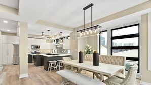 Cocina moderna con una isla central, comedor con banco y un amplio ventanal con vistas a la ciudad.