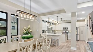A modern kitchen with a central island, pendant lighting, and a dining area with wooden chairs. - Hard to find, beautiful 4 bedroom luxury villa (Ocean City)