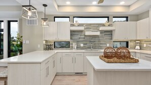 A modern kitchen with light wood cabinetry, a large island, and pendant lighting. - Hard to find, beautiful 4 bedroom luxury villa (Ocean City)