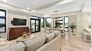 A spacious living room with a large sofa, a dining area with a table and chairs, and a TV mounted on the wall. - Hard to find, beautiful 4 bedroom luxury villa (Ocean City)