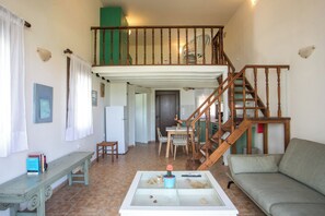 A spacious living area with a wooden staircase, a glass-top coffee table, and a sofa.