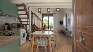 A kitchen with a washing machine, wooden chairs, a dining table, and a staircase. - Stylish sea view studio Artemis, Rhodes-Ialysos (Ialisos)