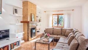 Una sala de estar con chimenea, un sofá, una mesa de centro y un televisor.