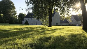 A grassy field with a stone building in the background.