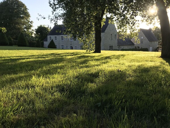 A grassy field with a stone building in the background.
