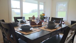 Une table à manger dressée pour six personnes, avec des assiettes, des bols et des couverts noirs, ainsi qu'un vase rempli de fleurs.