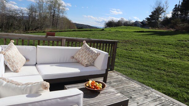 Une terrasse en bois avec un canapé blanc et un saladier rempli de fruits.