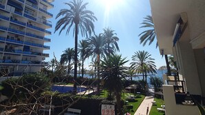 A multi-story building with balconies, a pool area with lounge chairs, and palm trees. - Skol 128 - Great 1-Bedroom Apartment with Sea Views (Marbella)
