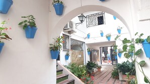 Ein gewölbter Gang mit Blumentöpfen, einer Treppe und einem Schild mit dekorativen Elementen.