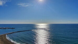 Ein Strand mit blauem Himmel und der Sonne, die über dem Wasser scheint.
