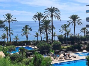 A resort with multiple swimming pools surrounded by palm trees and a view of the ocean. - Skol 206 - Spacious 2-Bedroom Duplex Holiday Home (Marbella)