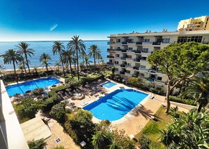 A resort with two swimming pools, palm trees, and a view of the ocean. - Skol 302 - Superb 1-Bedroom Duplex Apartment in Skol Marbella (Marbella)