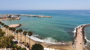A coastal area with a beach, a marina, and a rocky breakwater.