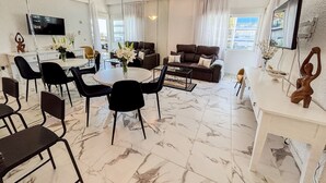A modern living room with a dining area, a sofa, a TV, and a large mirror. - Skol 326 - Attractive 1 Bed Apartment with Sea View in Skol Marbella (Marbella)
