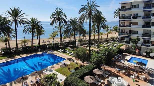 A resort with a pool, palm trees, and a beach view.