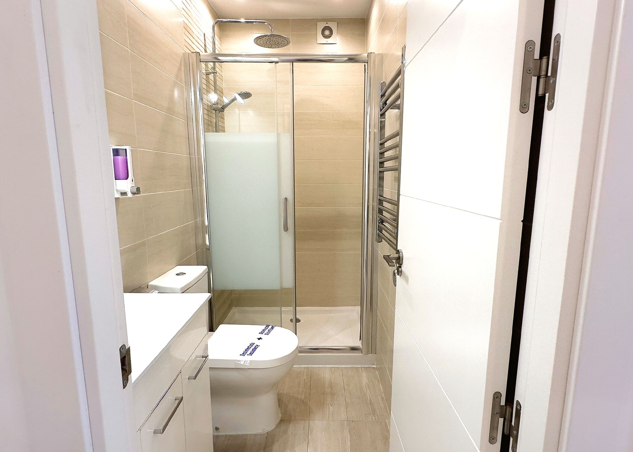 A modern bathroom with a glass-enclosed shower, a toilet, and a sink.