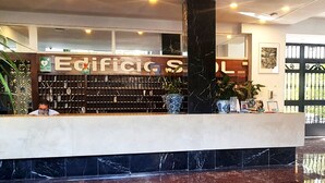A reception area with a marble counter, a large black pillar, and a sign reading "Edificio SOL". - Skol 427 - Spacious 1-Bedroom Apartment with Sea Views in Skol Marbella (Marbella)