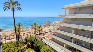 A beachfront hotel with multiple balconies, a pool area, and palm trees. - Skol 438 - Lovely 1 Bed Apartment with Wi-Fi + Sea Views in Skol Marbella (Marbella)