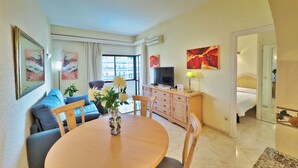 Una habitación de hotel con comedor, sofá, televisión y cama.