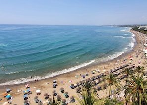 A beach with rows of sun loungers and umbrellas, a sandy shore, and the ocean. - Skol 617 - Fantastic 2-Bedroom Corner Duplex with Amazing Sea Views (Marbella)