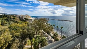 Un balcone con vista sul mare, edifici e vegetazione.