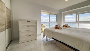 Una camera da letto con un letto, una cassettiera e vista sul mare.
