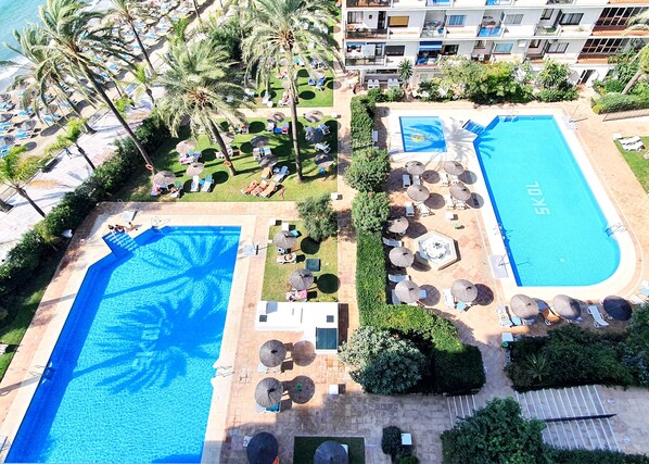 Et resort med to swimmingpools, palmer og loungeområder.