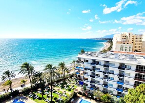 A hotel with a rooftop pool, sun loungers, and a view of the ocean.
