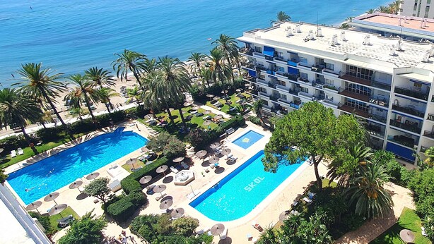 Et hotel med to swimmingpools, en strand og havudsigt.