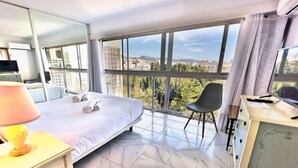 Una habitación de hotel con una cama grande, un escritorio con lámpara, una silla y un televisor.