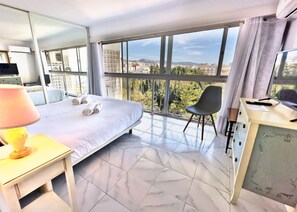 Ein Hotelzimmer mit einem großen Bett, einem Schreibtisch mit Lampe, einem Sessel und einem Fernseher.
