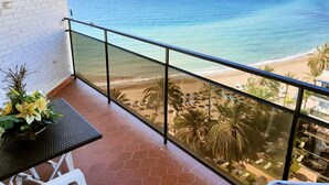 A balcony with a glass railing overlooking a beach. - Skol 803. Apartment With Amazing Views In Edificio Skol (Marbella)