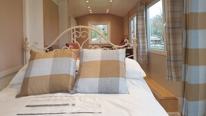 Une chambre à coucher avec un lit, des oreillers, une fenêtre et une vue sur l’extérieur.