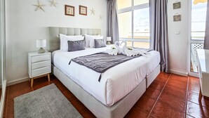 A hotel room with a large bed, a nightstand, a window with curtains, and starfish decorations on the wall.