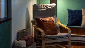 A room with a wooden chair, a cushion, a small rug, and a storage box. - Dreamy Forest Vibe Loft for Couples, Deck and Parking (Pittsburgh)