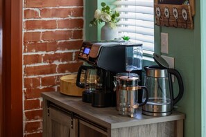 Eine Kaffeestation mit Kaffeemaschine, einem Glasbehälter und einem Metallkessel auf einer Holzauslage.