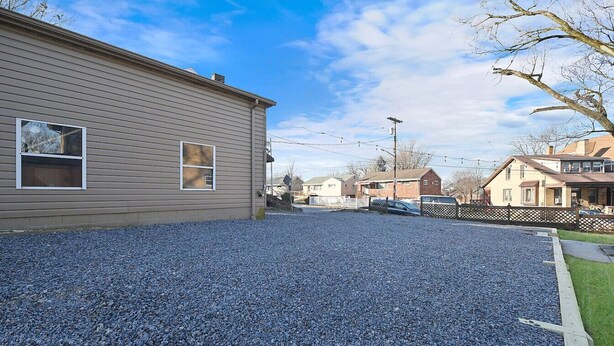 A residential area with a house featuring a gravel driveway and a wooden fence. - Dreamy Forest Vibe Loft for Couples, Deck and Parking (Pittsburgh)