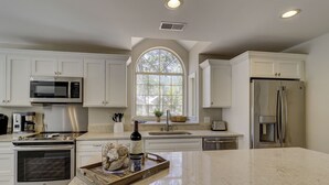 A modern kitchen with white cabinetry, stainless steel appliances, a large island, and a window with a view. - New Listing Wonderful Updated Home. Bikes & Beach Gear included (Hilton Head Island)