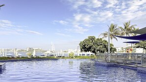 Ein Pool mit Blick auf eine Stadtlandschaft und Palmen.