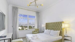 Ein Hotelzimmer mit einem großen Bett, einem Schreibtisch, einem Sessel und Blick auf die Stadt.