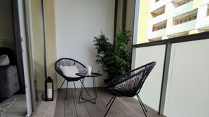 A balcony with two black chairs, a small table, a potted plant, and a candle. - Apartament Glamour - 365PAM (Kolobrzeg)