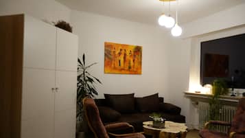 A living room with a sofa, two armchairs, a coffee table, and a painting on the wall.