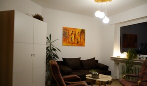 Ein Wohnzimmer mit einer Couch, zwei Sesseln, einem Couchtisch und einem Gemälde an der Wand.