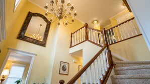 Eine prachtvolle Treppe mit einem Chandelier, einem Spiegel und gerahmten Kunstwerken.