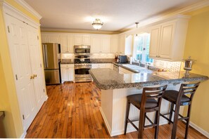 A kitchen with white cabinets, stainless steel appliances, a granite countertop, and wooden flooring. - Luxury Home in a Resort-Like Estate (Carbondale)